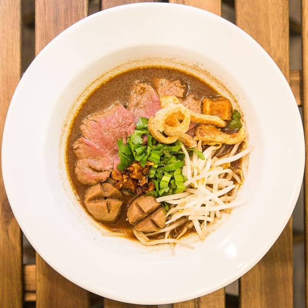Close-up of a Kao Sarn Thai Street Food noodle dish with beef, meatballs, and bean sprouts.