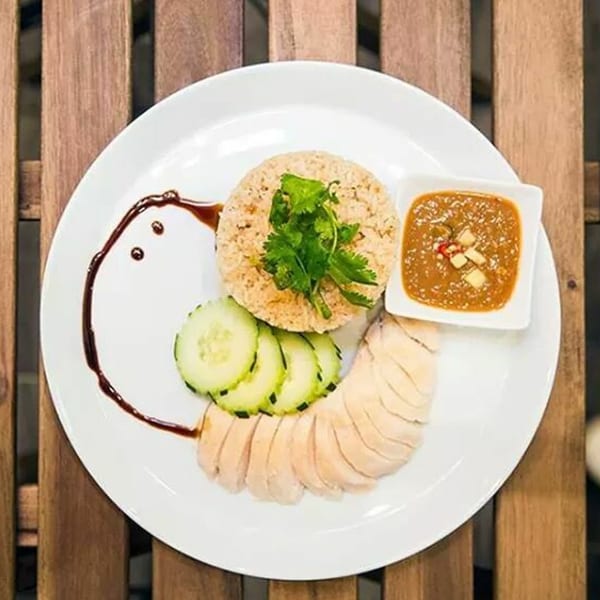 Kao Sarn Thai Street Food's Khao Man Gai, with sliced chicken, rice, cucumbers, and dipping sauce.