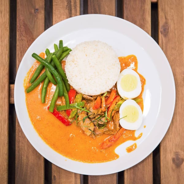Kao Sarn Thai red curry with beef, rice, green beans, bell peppers, and hard-boiled eggs.